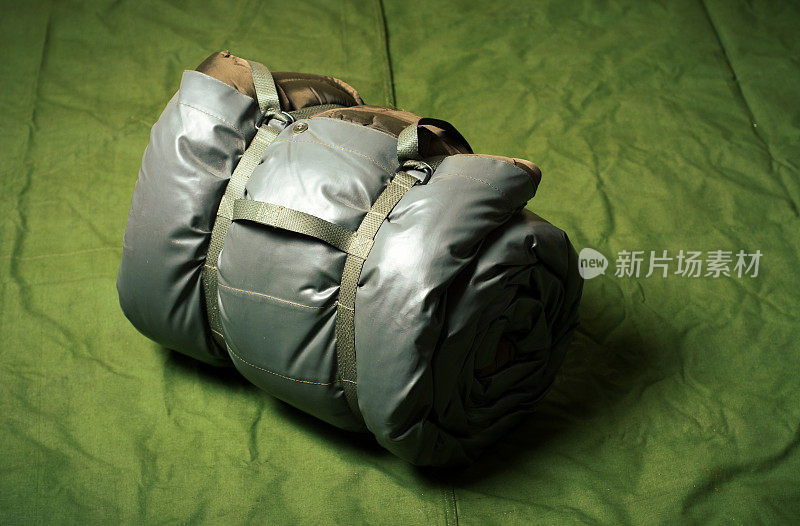 Military sleeping bag wrapped on army tent